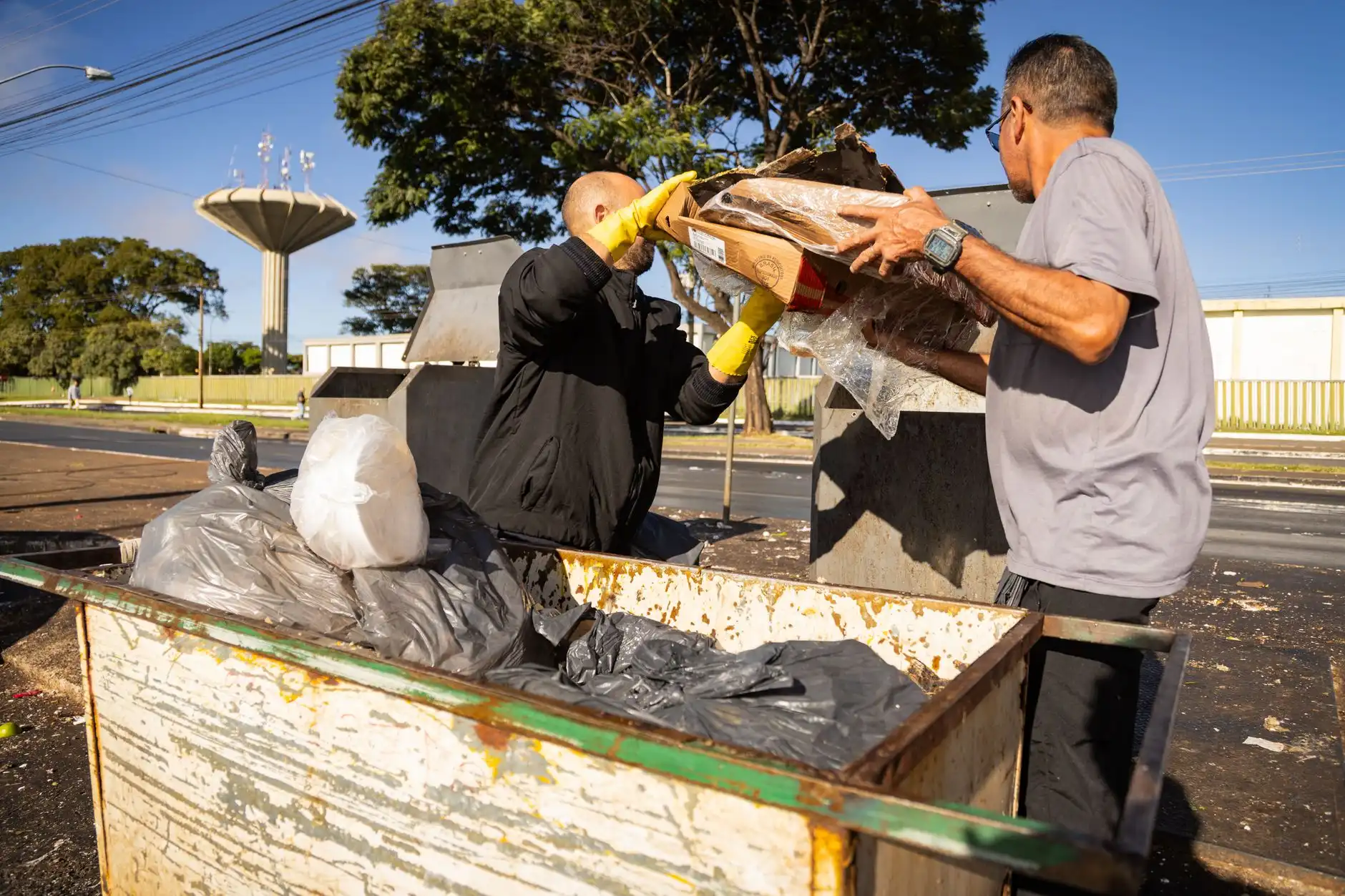 Two workers lifting old furniture into a dumpster