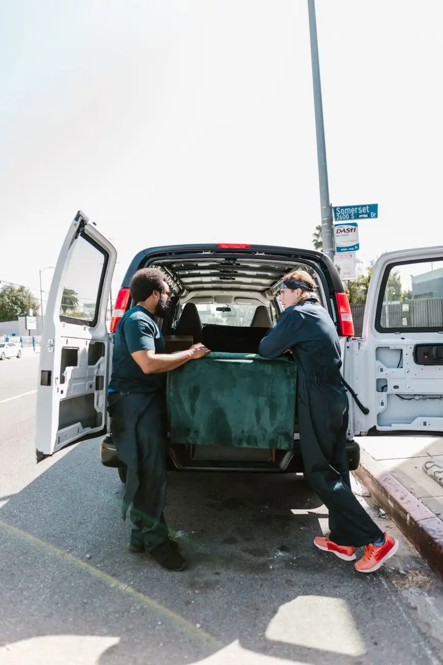 Movers loading unwanted items into a hauling van