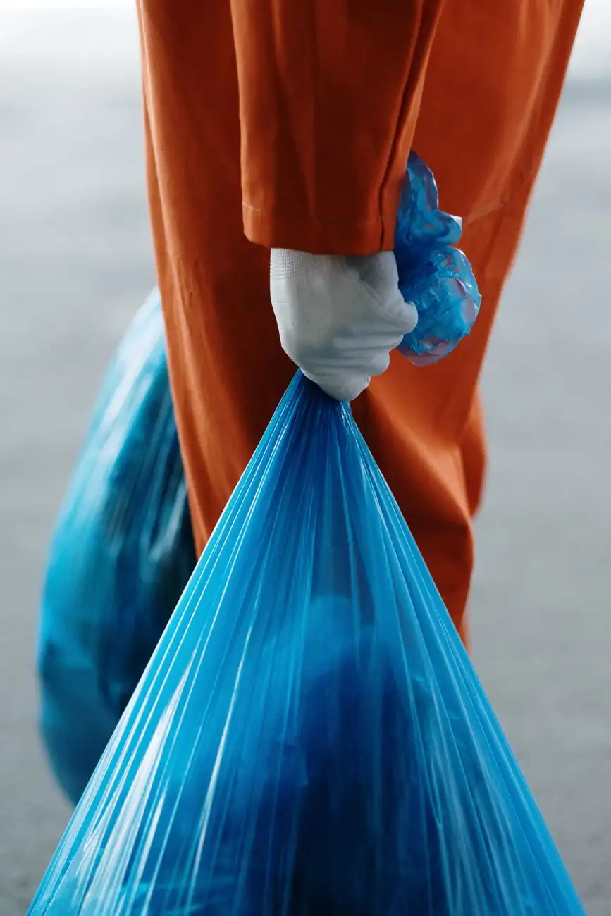 Hauler in work uniform carrying bagged debris